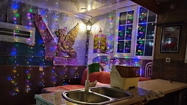 Una cocina con un lavamanos, una silla roja y una pared decorativa con luces.