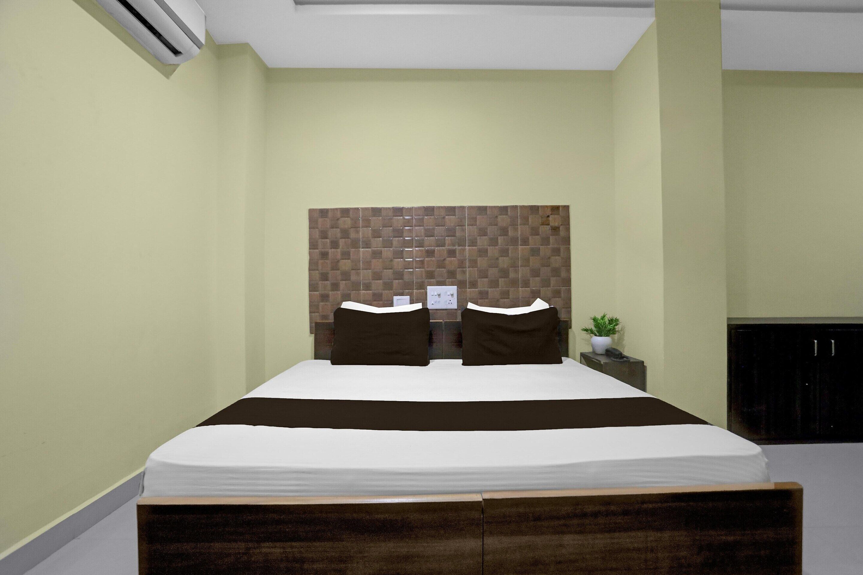 Un dormitorio ordenado con cama, cabecero, mesita de noche y una pequeña planta en maceta.