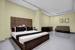 Ein Schlafzimmer mit einem großen Bett, einem dunklen Kopfteil, einer Couch und einem an der Wand befestigten Schrank.