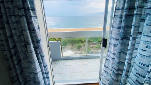 Ein Balkon mit Blick aufs Meer, Vorhänge und ein Fliesenboden.