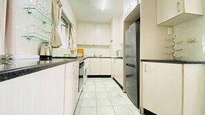 Eine Küche mit weißen Schränken, einem schwarzen Kühlschrank und einem gefliesten Boden.