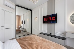 A modern hotel room with a large bed, a TV mounted on the wall, a mirror, and a sliding door leading to a bathroom. - Atmosphera ArCadia Apartments (Odesa)
