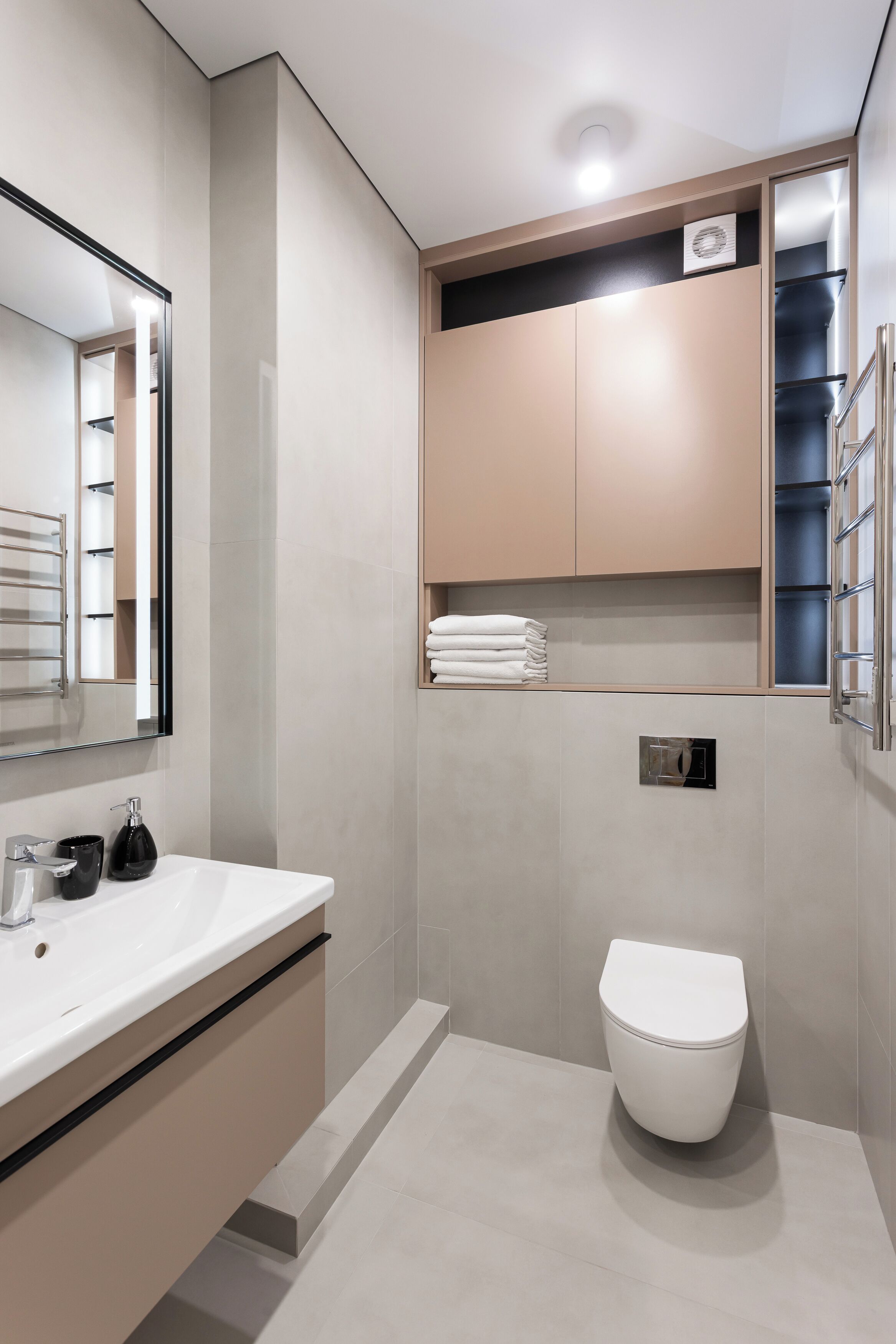 A modern bathroom with a white sink, a toilet, and a mirror.