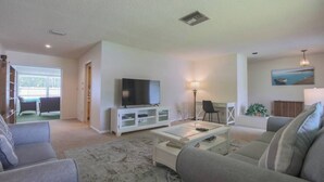 A living room with a flat-screen TV, a coffee table, and two sofas. - Cozy Private Unit w/ Shared Heated Pool (Cape Coral)