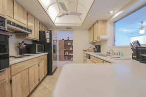 Una cocina moderna con armarios de madera, un microondas, un refrigerador y un ventanal con vistas.