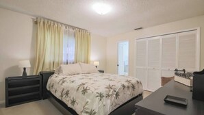 A bedroom with a bed, bedside tables, a desk, and a wardrobe. - Cozy Private Unit w/ Shared Heated Pool (Cape Coral)