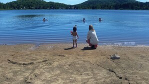 A beach with a lake, a sandy shore, and a hilly landscape in the distance. - Log cabin Laurentians | 5 bedrooms | trails, fireplace, spa, pets allowed (Sainte-Lucie-des-Laurentides)