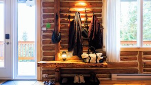 A log cabin interior with a bench, hanging bags, and a lantern. - Log cabin Laurentians | 5 bedrooms | trails, fireplace, spa, pets allowed (Sainte-Lucie-des-Laurentides)