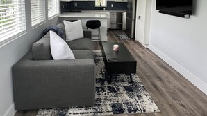 Een moderne woonkamer met een grijze bank, een zwarte salontafel en een plafondventilator.