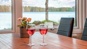 Une table avec deux verres à vin et une plante en pot, près d’une fenêtre donnant sur un lac.
