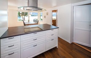 A kitchen with a dark countertop, white cabinets, and a stainless steel range hood. - Cozy vacation home by the lake in southern Sweden (Hallaryd)