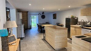 Une cuisine moderne dotée d’un îlot central en bois, d’appareils électroménagers intégrés et d’un coin repas offrant une vue sur l’extérieur.