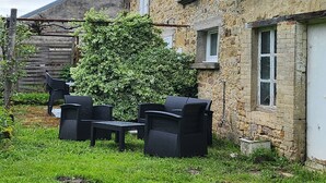 Un bâtiment en pierre doté d’un patio-jardin aménagé avec du mobilier d’extérieur.