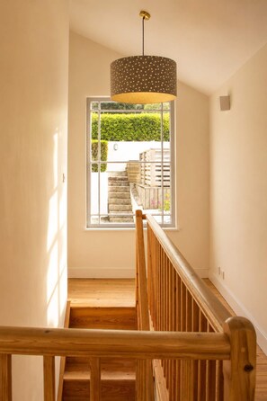 A staircase with wooden railings leading to a window with a view of a stone staircase outside. - The Captains Penwerris - By Rowes Retreats (Falmouth)