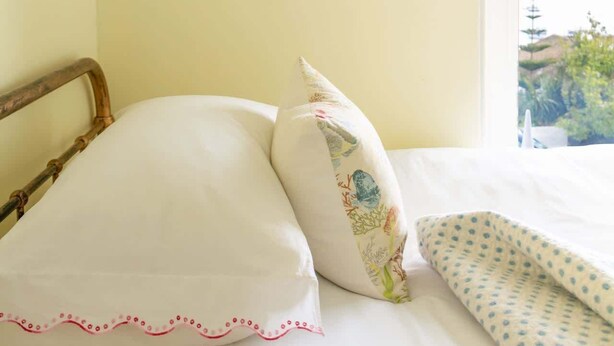 A bedroom with a bed, pillows, a framed picture on the wall, and a window with a view. - The Captains Penwerris - By Rowes Retreats (Falmouth)