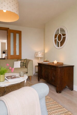 Un salon comprenant un canapé, une table basse, une lampe et un meuble en bois.