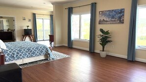Une chambre spacieuse avec un grand lit, une plante en pot et une vue sur l’extérieur.