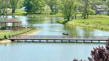 A serene lake with a wooden dock, a gazebo, and a small boat.