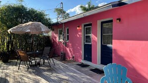 Een roze huis met een terras, een tafel met stoelen en een blauwe stoel.