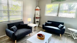 Een moderne woonkamer met twee donkere banken, een witte salontafel en een kleine witte tafel met een lamp.