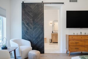 Ein modernes Wohnzimmer mit einer Schiebetür im Bauernhausstil, einem Flachbildfernseher, einem Holzschrank und einem weißen Sofa.