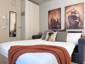 A bedroom with a bed, a wardrobe, a mirror, and two wall art pieces. - Casa Caterina - in the Heart of Porta Venezia (Milan)