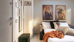 Quarto com cama, almofadas, cobertor, telefone fixado na parede e obras de arte.