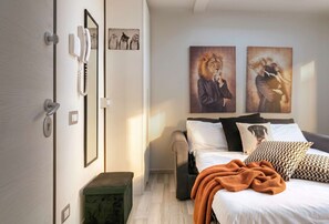 Ein Schlafzimmer mit Bett, Kissen, Decke, einem fest montierten Telefon und Kunstwerken.