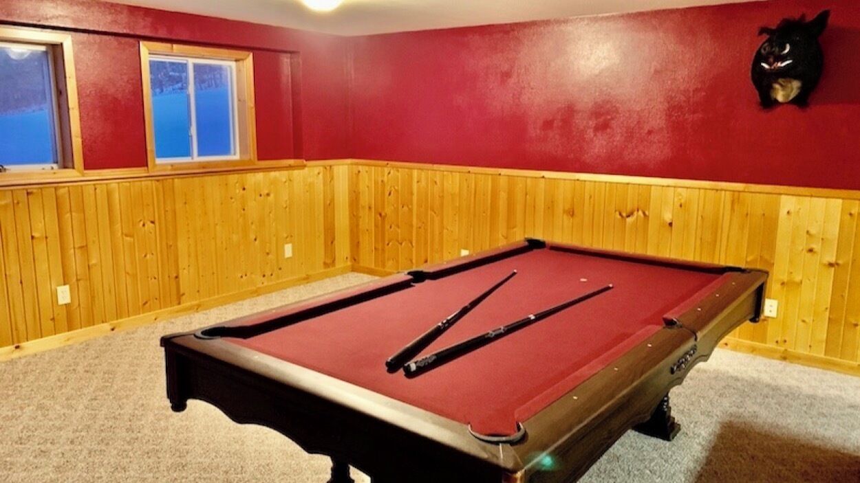 Een pooltafel in een ruimte met houten lambrisering en een rode muur.