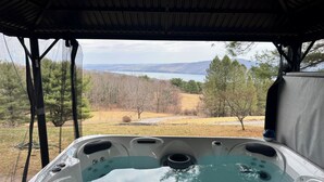 A hot tub with a view of a lake and hills.