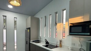 Una cocina moderna con microondas integrado, un lavabo y un refrigerador.