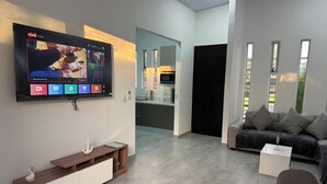 Una sala de estar moderna con un televisor de pantalla plana, un sofá, una mesa de centro y una consola de madera.