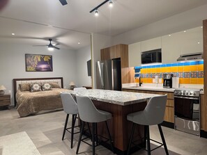 A modern kitchen with a central island, bar stools, a refrigerator, a microwave, and a stove. - Casa Camille at Oasis Rivera del Rio (Puerto Vallarta)