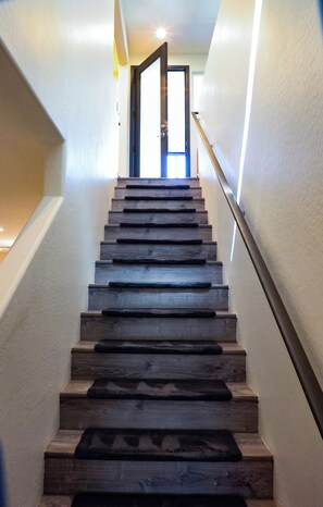 Una escalera de madera con barandilla que lleva a una puerta.