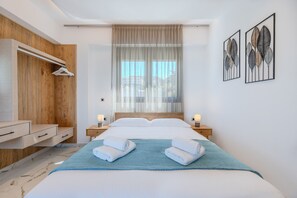 A modern bedroom with a bed, bedside tables, a wooden wardrobe, and artwork on the wall. - Elmar bay Villa (Hersonissos)