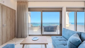Una sala de estar moderna con un sofá, una mesa y vista al mar a través de amplios ventanales correderas.