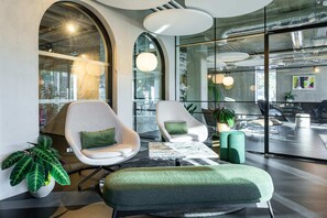 Et moderne loungeområde med buede siddepladser, et sofabord og krukker med planter.