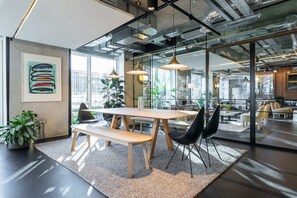 A modern office space with a wooden table, black chairs, and a large window. - AEA-Woodward Square (Dublin)