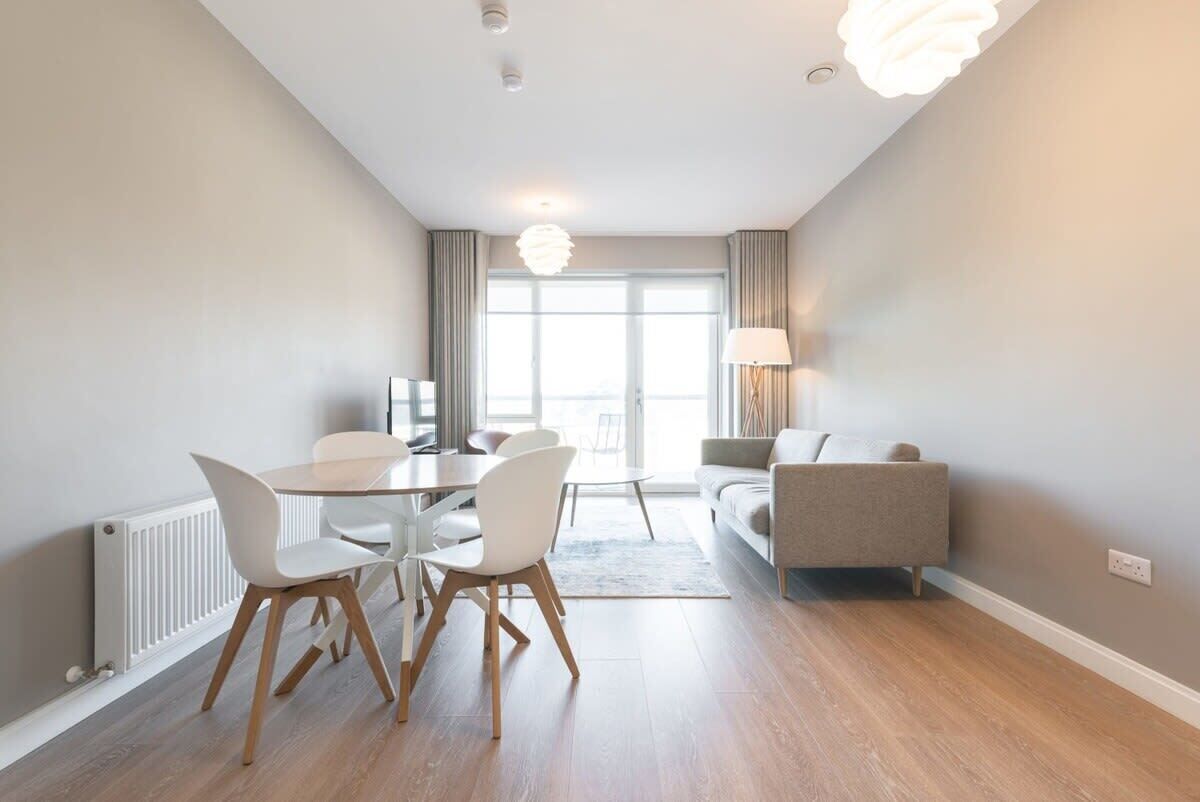 A modern living room with a dining area, a sofa, and a lamp.