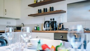A modern kitchen with a coffee maker, kettle, and shelves with containers. - Central Nottingham 3 Bed House with Driveway (Nottingham)