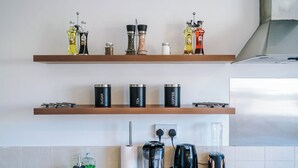 A kitchen with wooden shelves holding various kitchen items, a coffee maker, and a blender on the counter. - Central Nottingham 3 Bed House with Driveway (Nottingham)