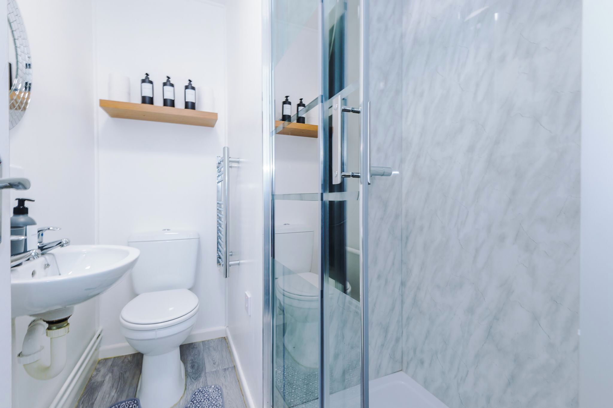 Een moderne badkamer met een glazen douchecabine, een wit wastafelmeubel en een toilet.