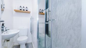 Een moderne badkamer met een glazen douchecabine, een wit wastafelmeubel en een toilet.