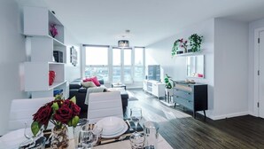 Un soggiorno moderno con zona pranzo, ampie finestre e vista sulla città.
