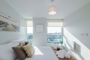 A modern bedroom with a large bed, a city view, a hanging light fixture, and a radiator. - Skyline 2BD/2BA Central Nottingham Free Parking (Nottingham)