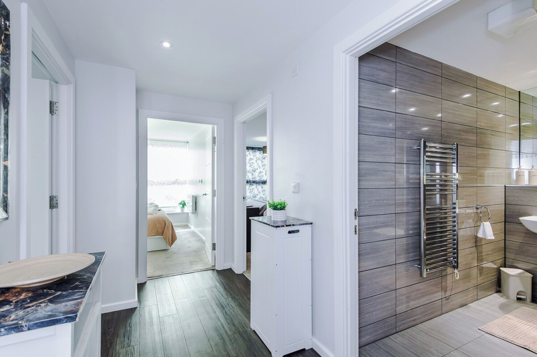 A modern bathroom with a large mirror, a towel rack, and a sink.