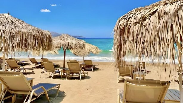 A beach with thatched umbrellas and lounge chairs. - Elysian Seaside Villa (Almyrida)