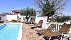 Una piscina con sillones de descanso y un patio de piedra.