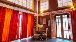 A dining area with a brick wall, wooden table, and chairs. - Bumblebee an Artistic Private Villa w/Splash Pool and Pet Friendly (Dehradun)