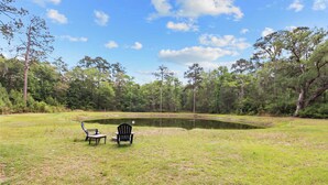 A pond with two chairs and a table in a grassy area surrounded by trees. - The Low Country Loft- Comfy 1BDRM Loft-4 Pass Golf Cart Included (Daufuskie Island)